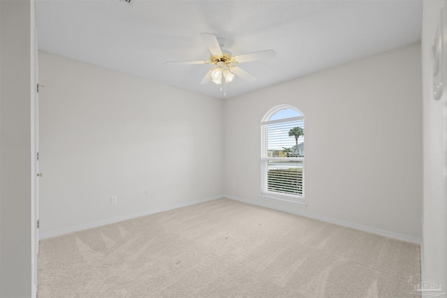 empty room featuring a ceiling fan, light colored carpet, and baseboards