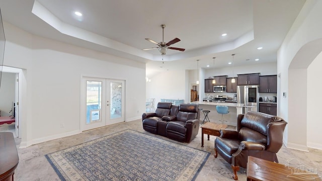 living room featuring a raised ceiling, ceiling fan, french doors, and sink