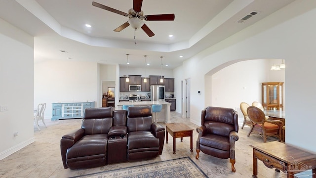 living room featuring a tray ceiling and ceiling fan