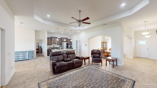 living room featuring a towering ceiling, a tray ceiling, and ceiling fan