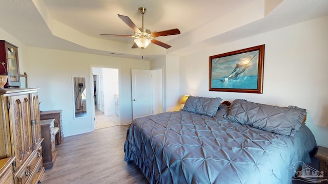 bedroom featuring hardwood / wood-style floors, ceiling fan, and a raised ceiling