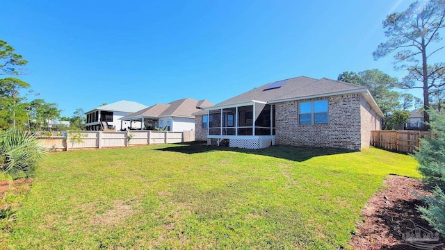 rear view of property featuring a yard and a sunroom