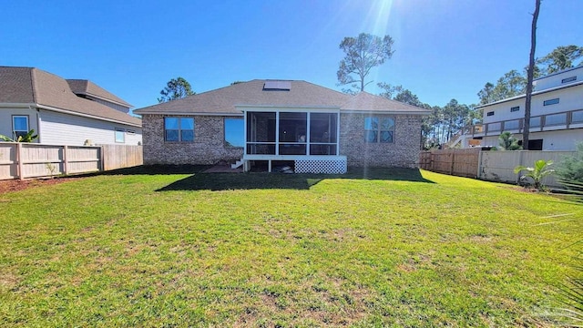 rear view of property featuring a sunroom and a lawn