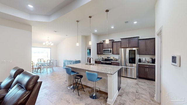 kitchen with hanging light fixtures, an island with sink, appliances with stainless steel finishes, and a breakfast bar area