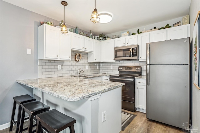 kitchen featuring kitchen peninsula, white cabinets, and stainless steel appliances