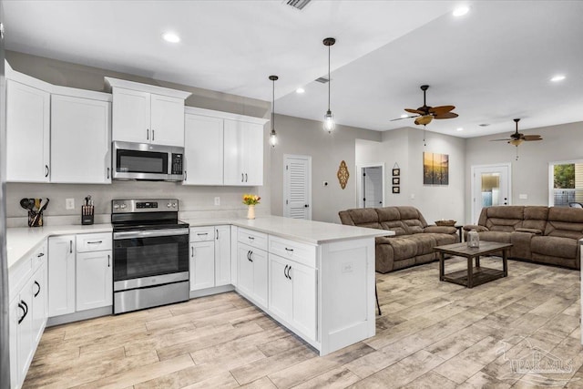 kitchen featuring stainless steel appliances, light countertops, open floor plan, white cabinetry, and a peninsula