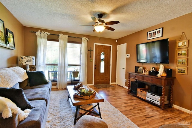 living room with ceiling fan, light hardwood / wood-style floors, and a textured ceiling