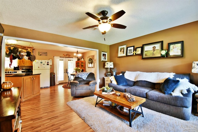 living room with ceiling fan, a textured ceiling, light hardwood / wood-style flooring, and french doors