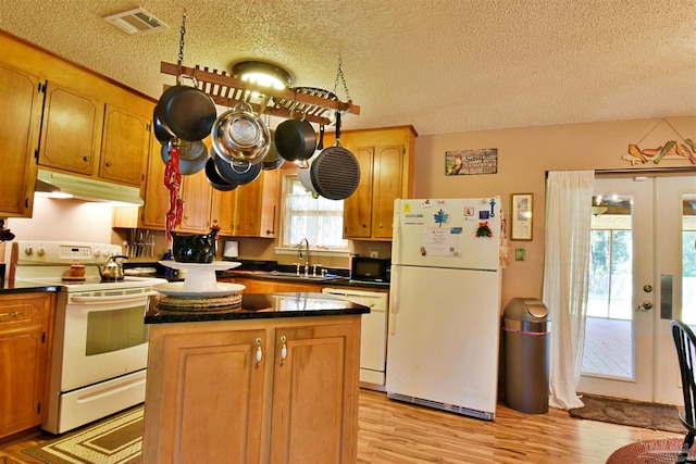 kitchen with white appliances, sink, light hardwood / wood-style floors, and a textured ceiling