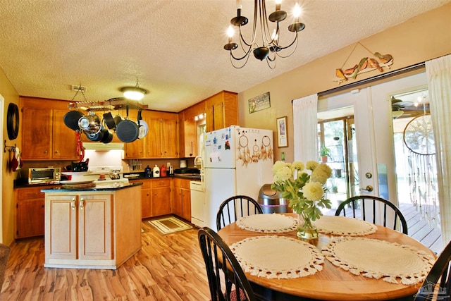 dining area featuring an inviting chandelier, sink, light hardwood / wood-style flooring, and a textured ceiling