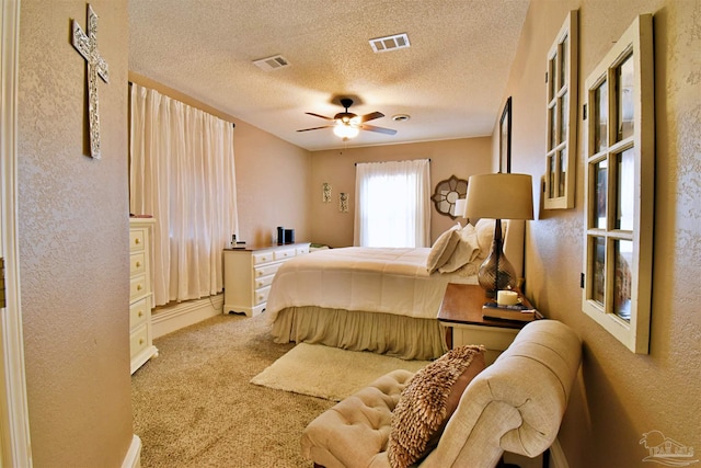 bedroom featuring light carpet, a textured ceiling, and ceiling fan