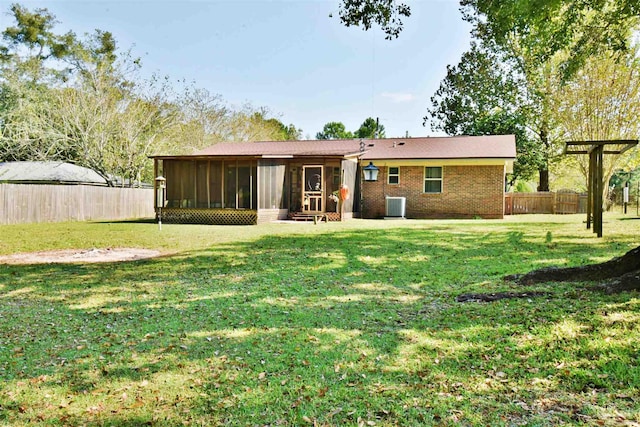 rear view of house featuring a sunroom, central AC unit, and a lawn