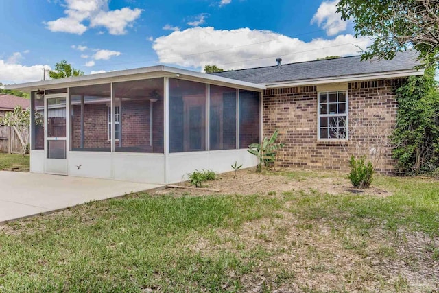 back of house with a sunroom, brick siding, and a lawn