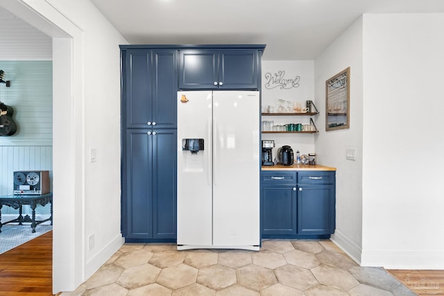 kitchen featuring blue cabinets, white refrigerator with ice dispenser, and light wood-type flooring