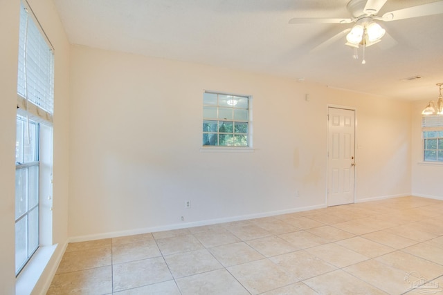 tiled empty room with plenty of natural light and ceiling fan with notable chandelier