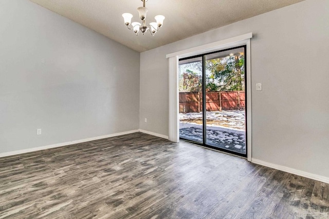 empty room with lofted ceiling, dark hardwood / wood-style floors, and a notable chandelier