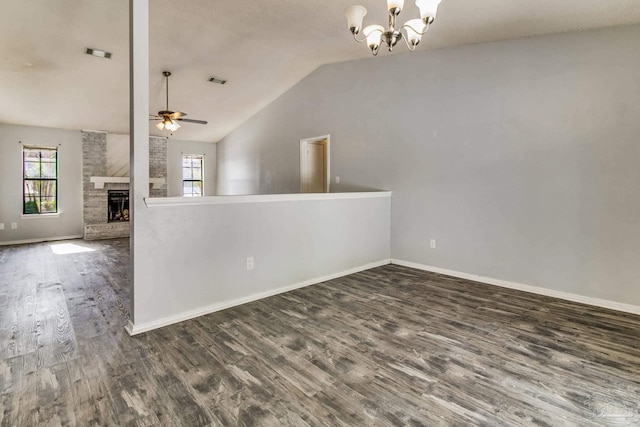 unfurnished room with lofted ceiling, dark wood-type flooring, ceiling fan with notable chandelier, and a fireplace