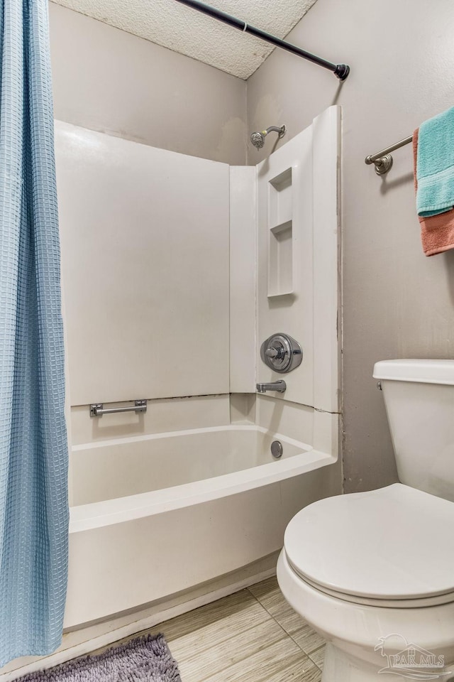 bathroom with toilet, shower / bath combo with shower curtain, and a textured ceiling