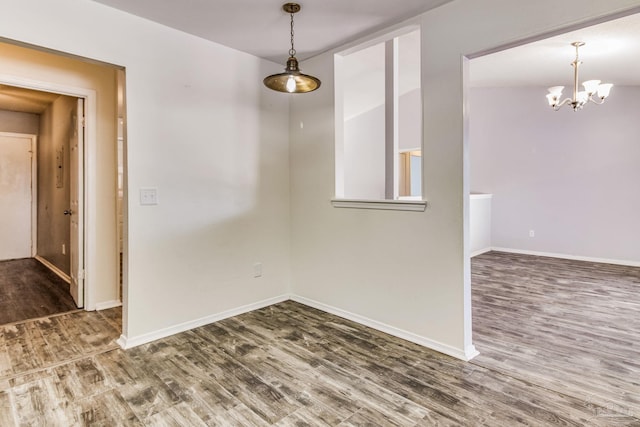 empty room featuring an inviting chandelier and dark wood-type flooring