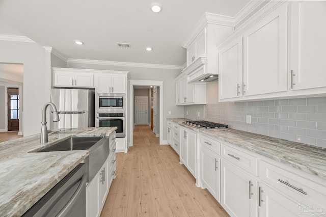6264 Howie Way, Pace, FL 32571 - kitchen featuring appliances with stainless steel finishes, white cabinetry, tasteful backsplash, crown molding, and light wood finished floors