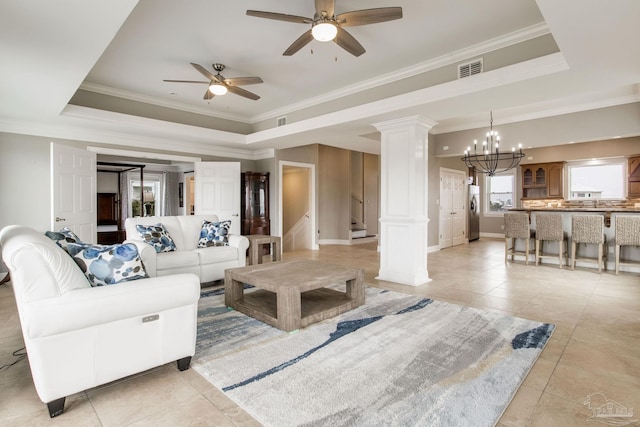 living room with a tray ceiling, crown molding, ceiling fan with notable chandelier, and visible vents