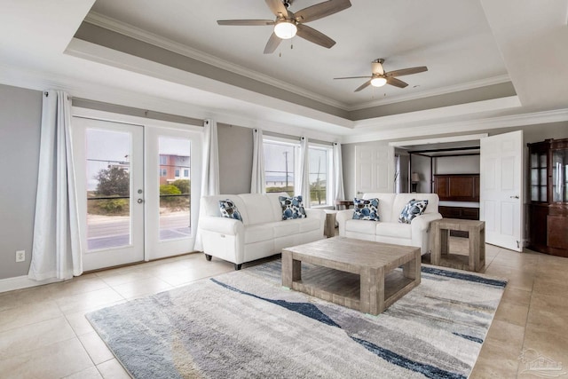 living room with ceiling fan, a tray ceiling, ornamental molding, light tile patterned flooring, and french doors