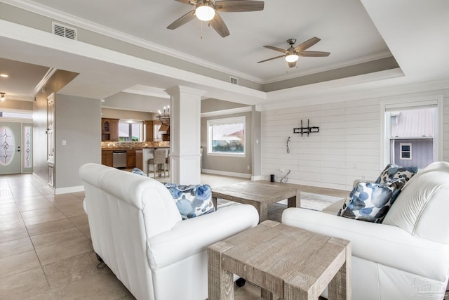living room featuring visible vents, baseboards, crown molding, and ceiling fan