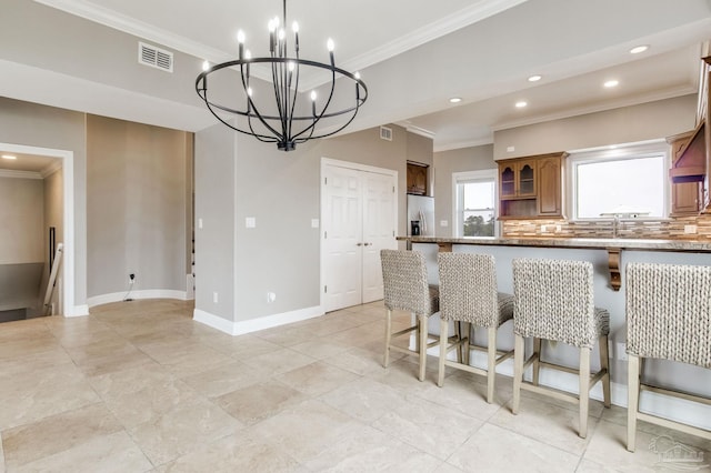 kitchen with stainless steel fridge with ice dispenser, ornamental molding, visible vents, and a kitchen breakfast bar