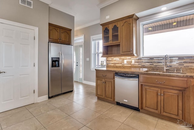 kitchen featuring tasteful backsplash, visible vents, brown cabinetry, stainless steel appliances, and a sink