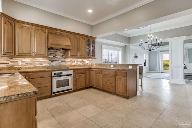 kitchen with crown molding, stainless steel oven, tasteful backsplash, a peninsula, and custom range hood
