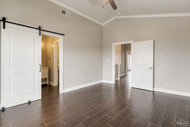 spare room featuring ceiling fan, vaulted ceiling, visible vents, a barn door, and dark wood-style flooring