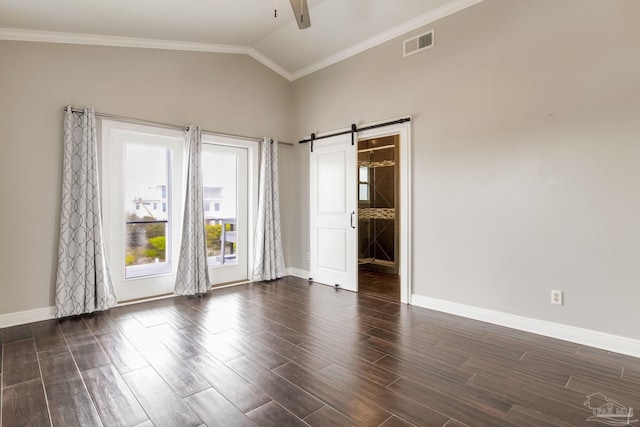 spare room featuring dark wood-style flooring, baseboards, a ceiling fan, a barn door, and visible vents