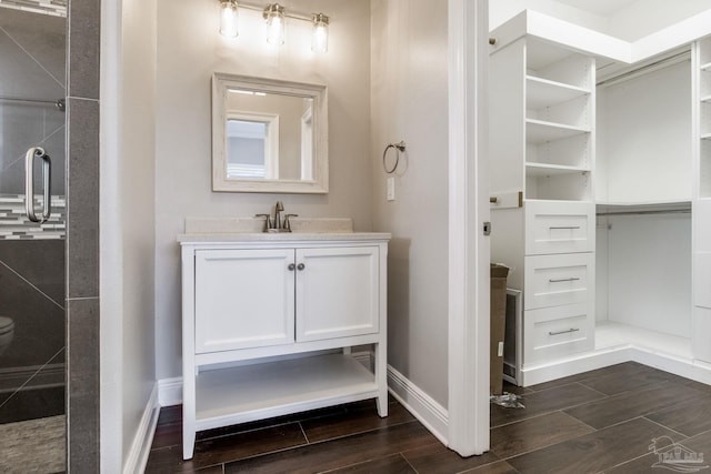full bath featuring vanity, baseboards, and wood finish floors