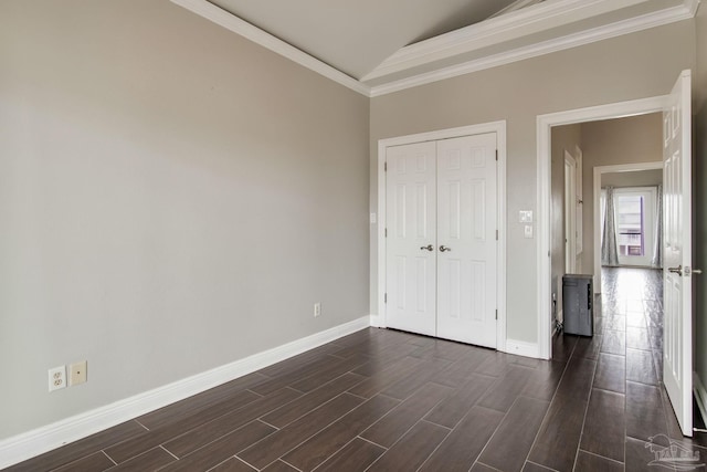 unfurnished bedroom with dark wood-style flooring, a closet, baseboards, and ornamental molding