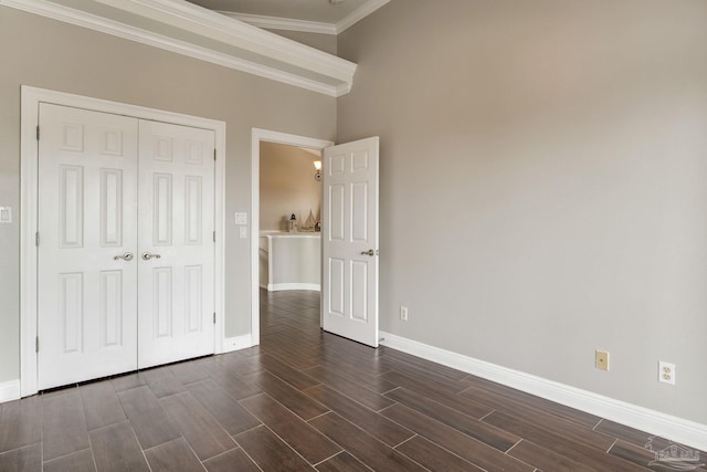 unfurnished bedroom featuring ornamental molding, baseboards, a closet, and wood finish floors
