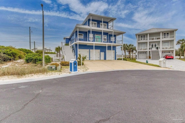 raised beach house with an attached garage, driveway, and stairs