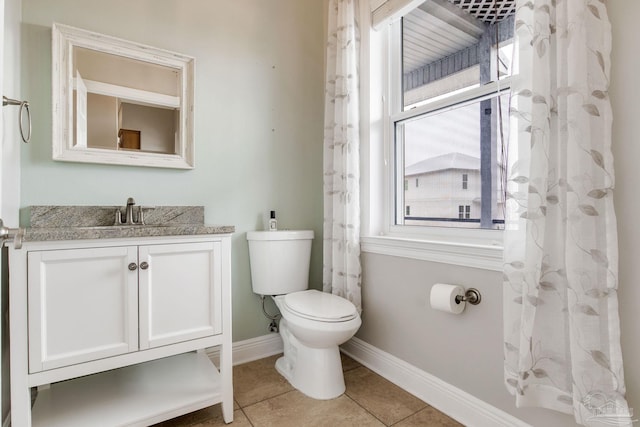 bathroom with tile patterned flooring, baseboards, toilet, and a healthy amount of sunlight