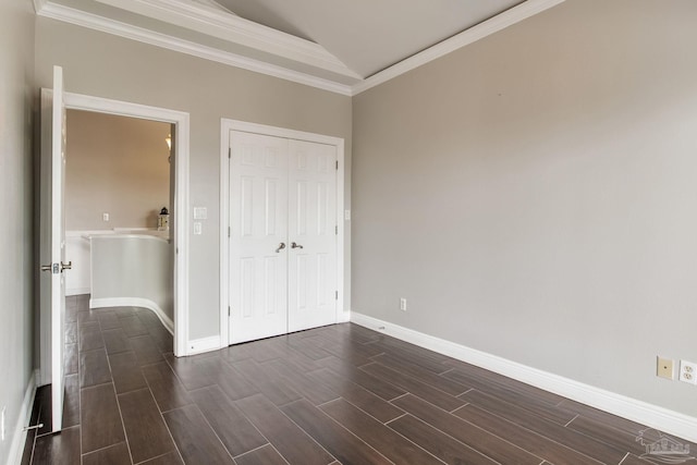 unfurnished bedroom featuring a closet, baseboards, crown molding, wood finish floors, and lofted ceiling