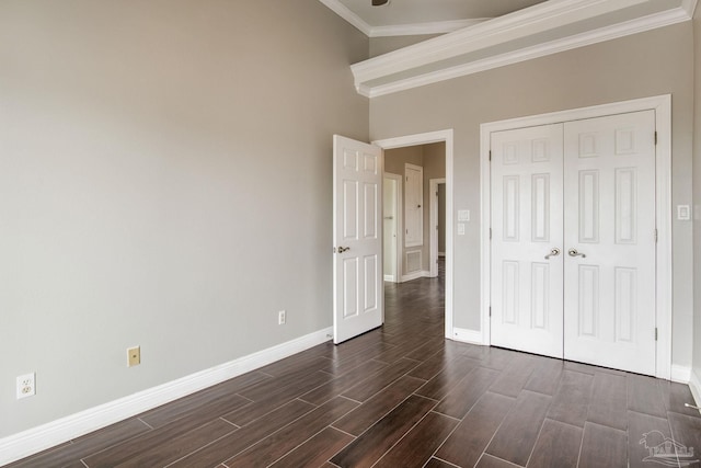 unfurnished bedroom featuring crown molding, a closet, dark wood-style flooring, and baseboards