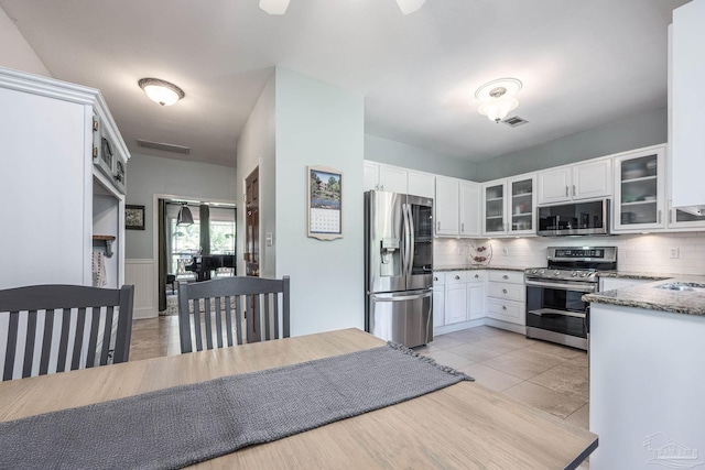 2205 Valle Escondido Dr, Pensacola, FL 32526 - kitchen featuring appliances with stainless steel finishes, tasteful backsplash, white cabinetry, glass insert cabinets, and stone counters