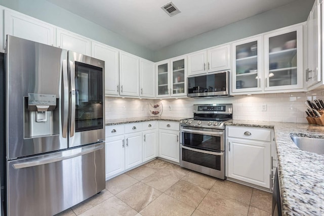 2205 Valle Escondido Dr, Pensacola, FL 32526 - kitchen featuring appliances with stainless steel finishes, decorative backsplash, white cabinetry, and light stone countertops