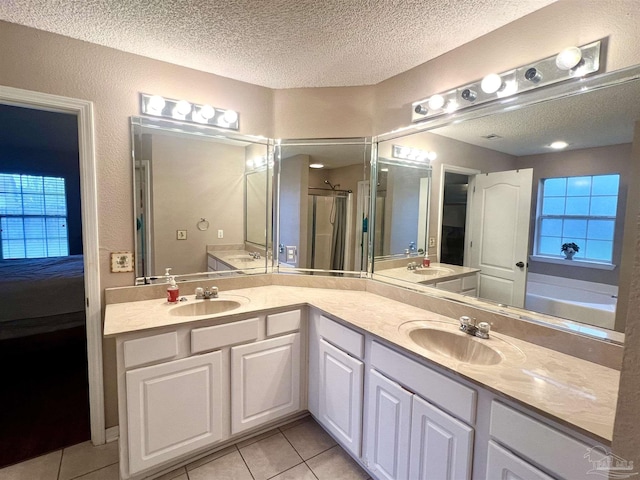 bathroom featuring double vanity, a textured ceiling, a sink, and tile patterned floors