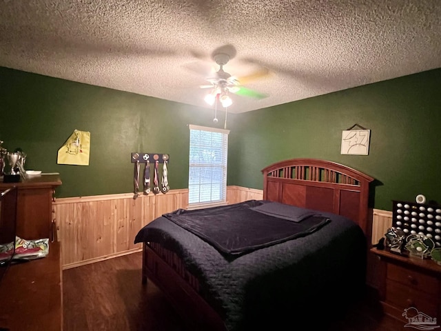bedroom with a wainscoted wall, wood finished floors, ceiling fan, and a textured ceiling