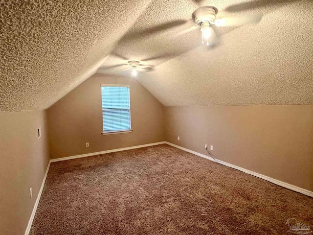 additional living space featuring lofted ceiling, carpet, baseboards, a textured ceiling, and a ceiling fan
