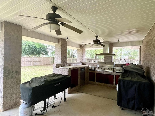 view of patio with an outdoor kitchen, a sink, fence, and a grill
