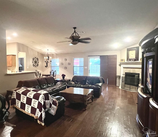 living room featuring ceiling fan with notable chandelier, a fireplace, lofted ceiling, and dark wood-type flooring