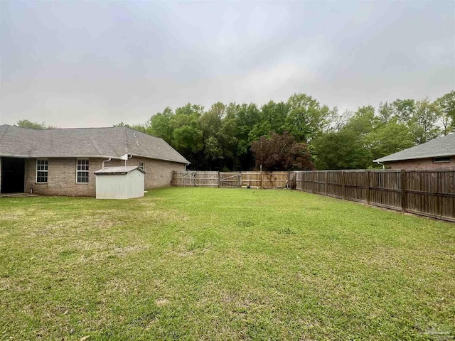 view of yard with a storage unit, a fenced backyard, and an outdoor structure