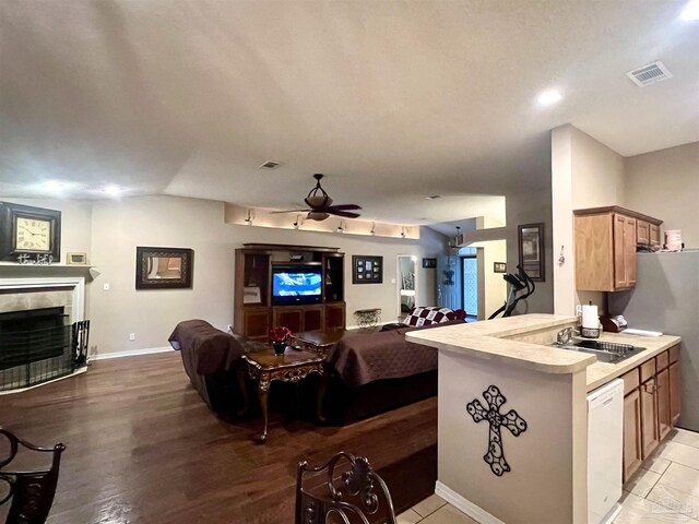 kitchen with a tiled fireplace, a sink, open floor plan, white dishwasher, and visible vents