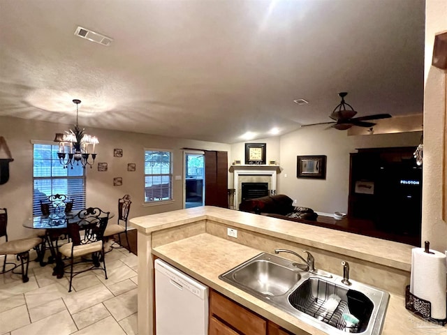 kitchen featuring light countertops, dishwasher, a tiled fireplace, a sink, and open floor plan