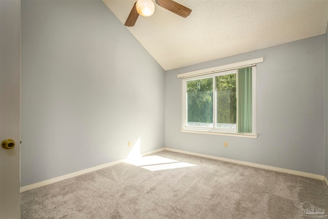 carpeted empty room featuring vaulted ceiling, ceiling fan, and a textured ceiling